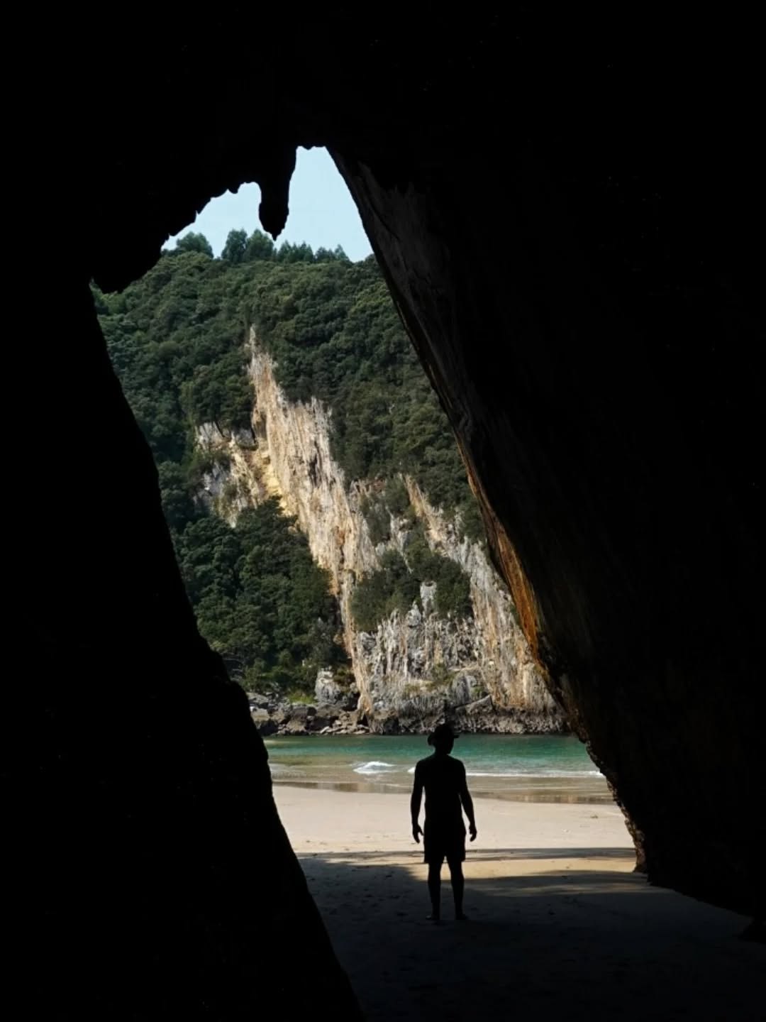 Photograph of a silhouetted figure inside a cave opening