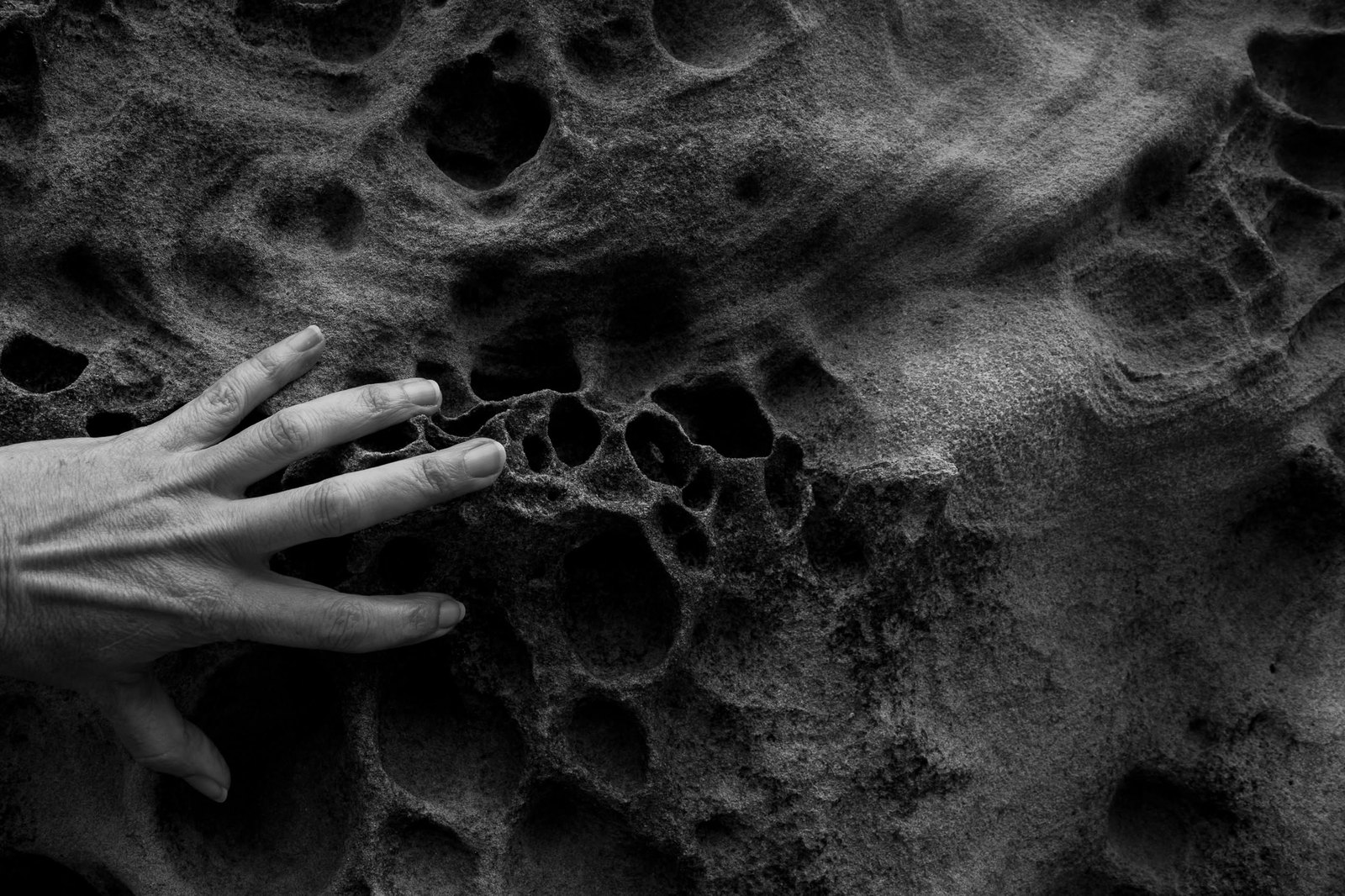 Photograph of a hand pressed into textured sand