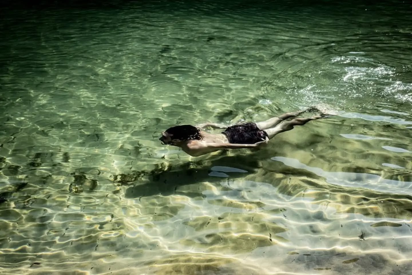 Photograph of a swimmer in clear green water