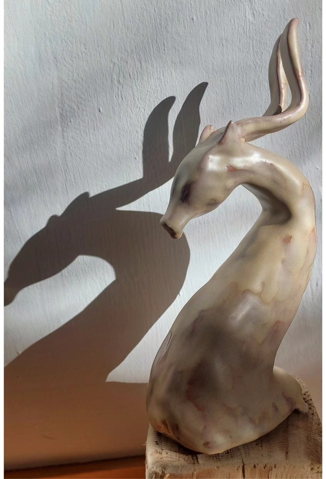 Pale glazed ceramic sculpture of a deer with long antlers