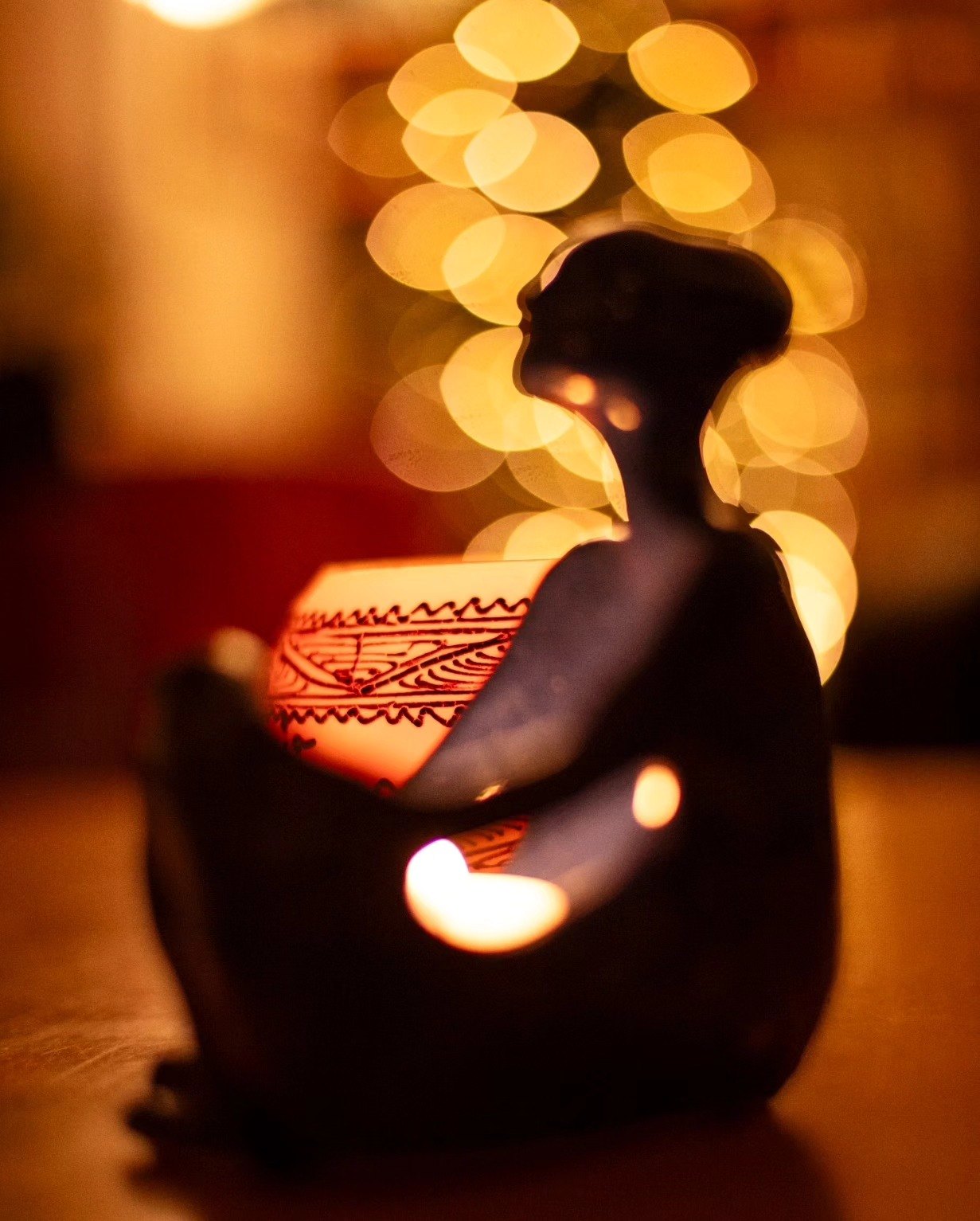 Ceramic candle holder shaped like a seated silhouetted figure