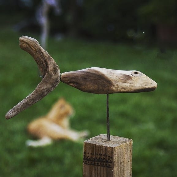 Driftwood sculpture of a bird in flight mounted on a wooden post